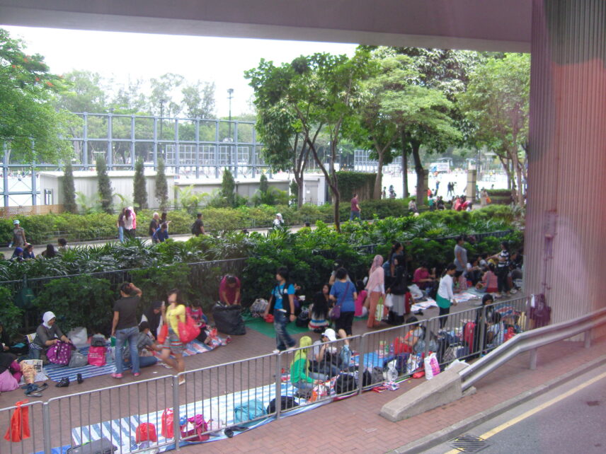 Photograph of a sidewalk filled with people next to a park