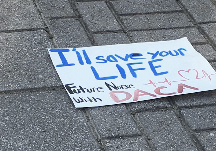 Photograph of a homemade protest sign laying on the ground