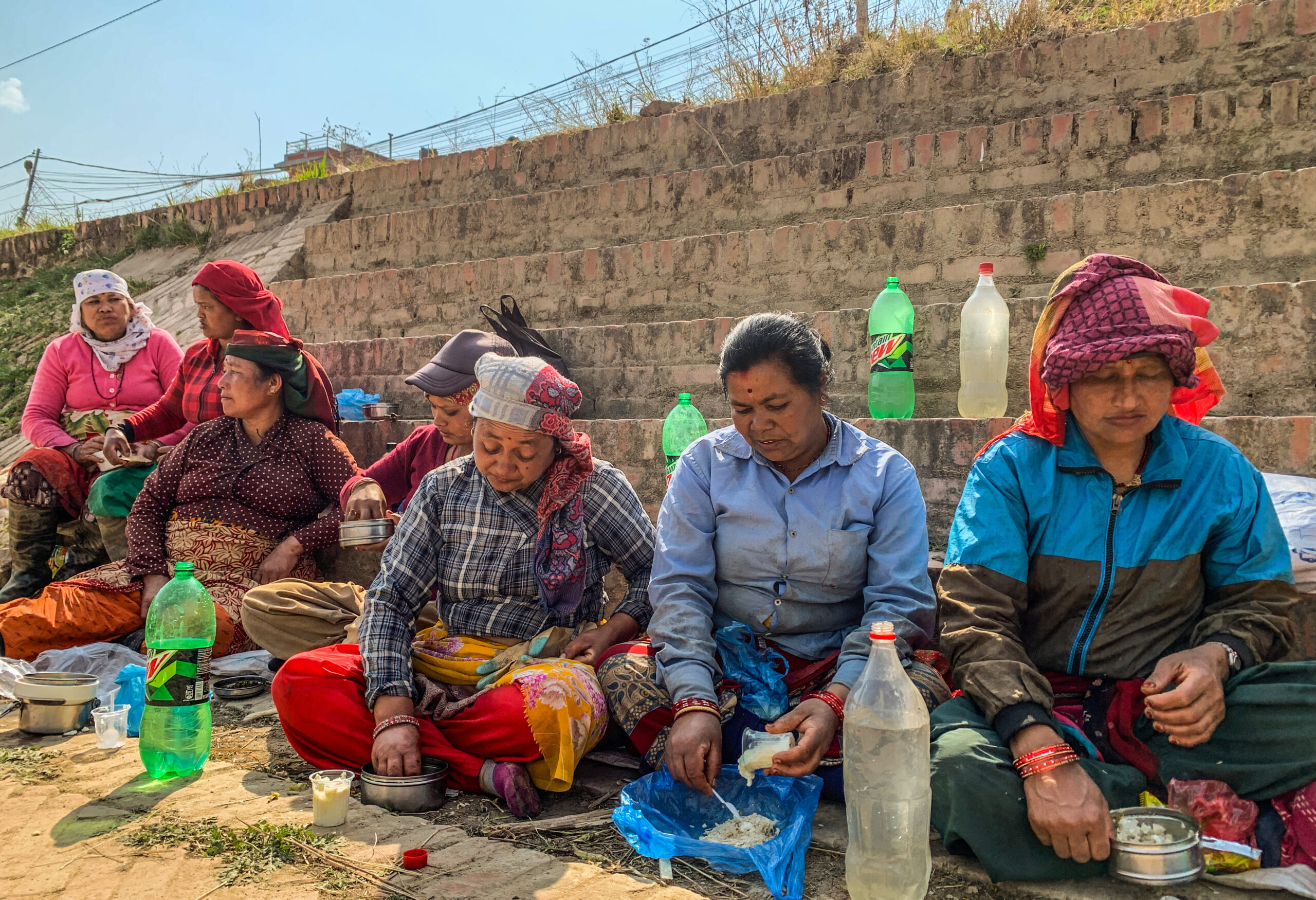 Figure 4: Women taking a break in between their work at a rebuilding site. They share home-cooked food and wrapped their heads in cloth to avoid the harsh afternoon sun.