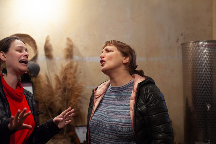Two women with lively expressions on their faces are conversing.