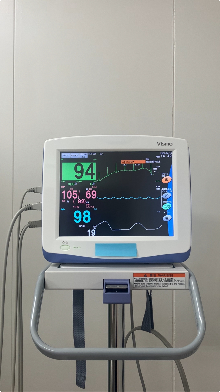 A Vital Signs Monitor with alarm sounding, top light flashing, and heart rate values highlighted due to high heart rate.