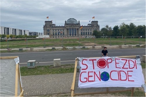 Poster saying “Stop Ezdi Genocide” standing in front of the Reichstag