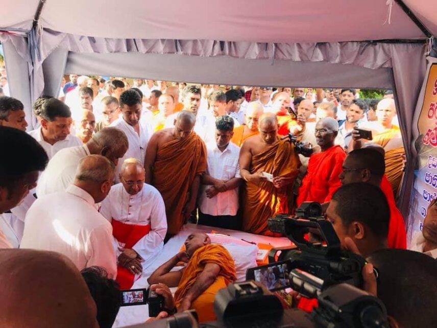 Picture showing Rathana Thera fasting, lying on his right side with his hand touching his head, reminiscent of the Buddha’s Parinibbāna posture.