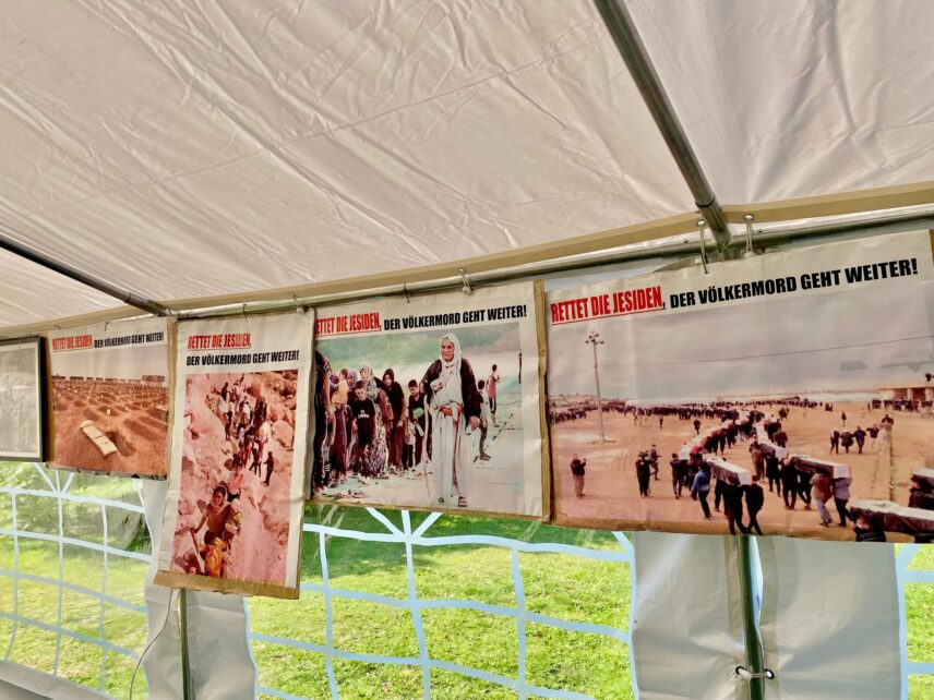 Posters with German text saying “Save the Yezidis: The Genocide Continues” hung in a tent.