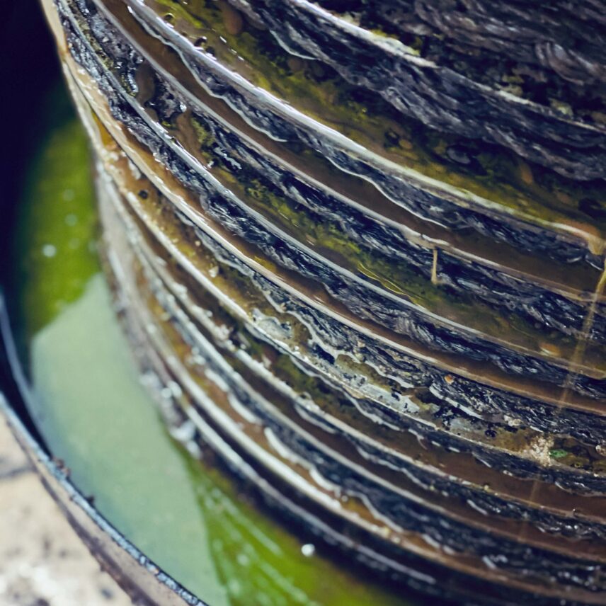 Stacked pressing mats and iron weights extracting olive oil in a traditional mill.