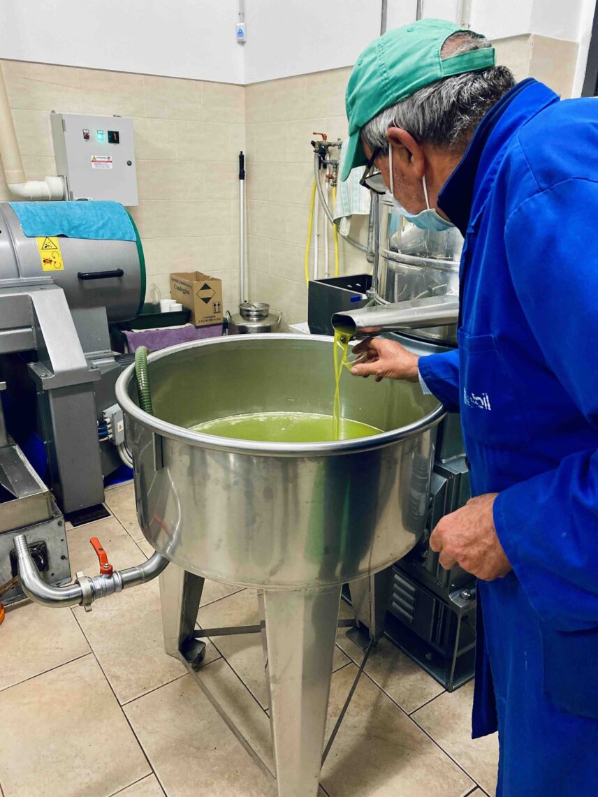Worker about to taste freshly pressed olive oil from a centrifuge in an olive oil mill.