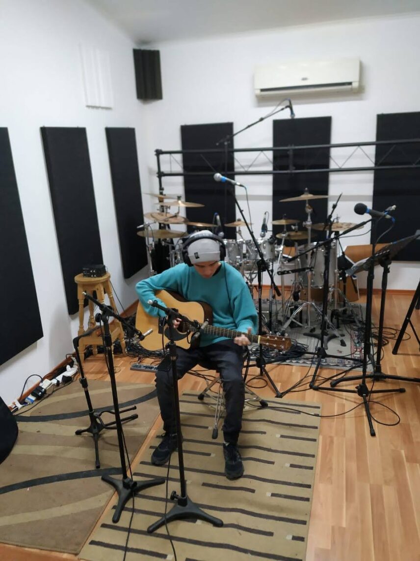 Agustín Lino playing guitar in a music studio.