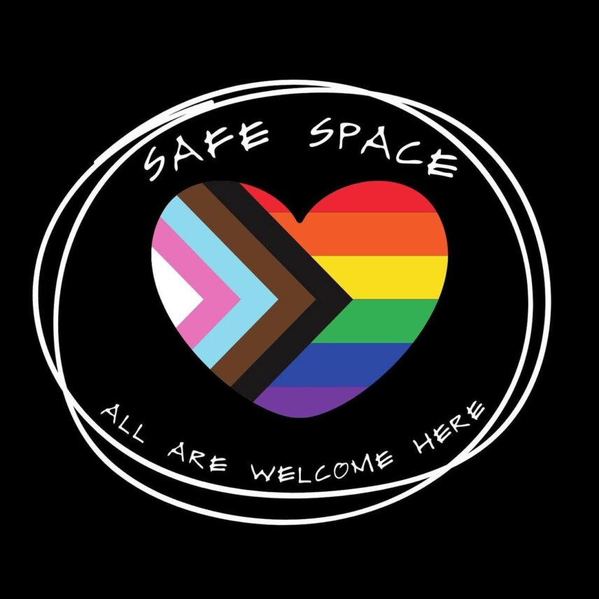 The 2018 Progress Pride Flag in a heart, surrounded by the words "Safe space, all are welcome here," against a black background.