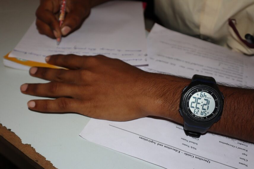 Figure 7: Time: Struggling in the present for the future, a student keeps a watch on his wrist to track his schedule.