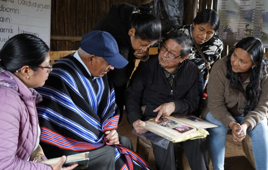 Kamëntšá elders and Ayentš Collective members examine a historical photo album together.