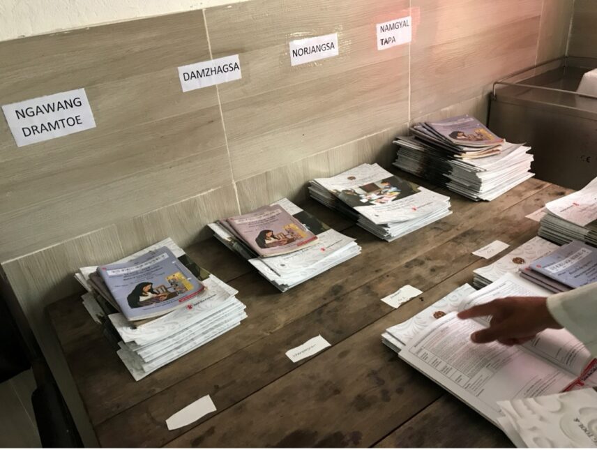 A photo of a hand pointing at an open document on a table stacked with handbooks for patients