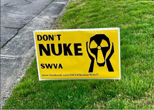 Along a roughly paved street, a bright yellow road sign that reads “Don’t Nuke SWVA” sits on green grass. The three-pronged nuclear symbol is elongated with two hand-like shapes along its sides to emulate Edvard Munch’s “The Scream.”