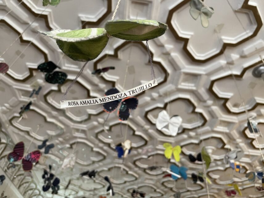 Decorative plaster ceiling hung with fabric butterflies and slips of white paper with names written on them