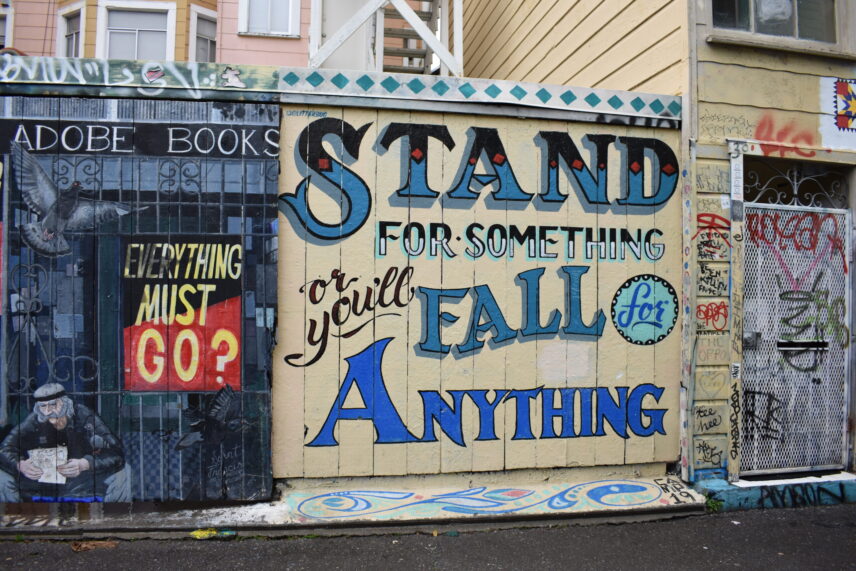 An image of a mural on a city street that reads "Stand for something or you'll fall for anything."